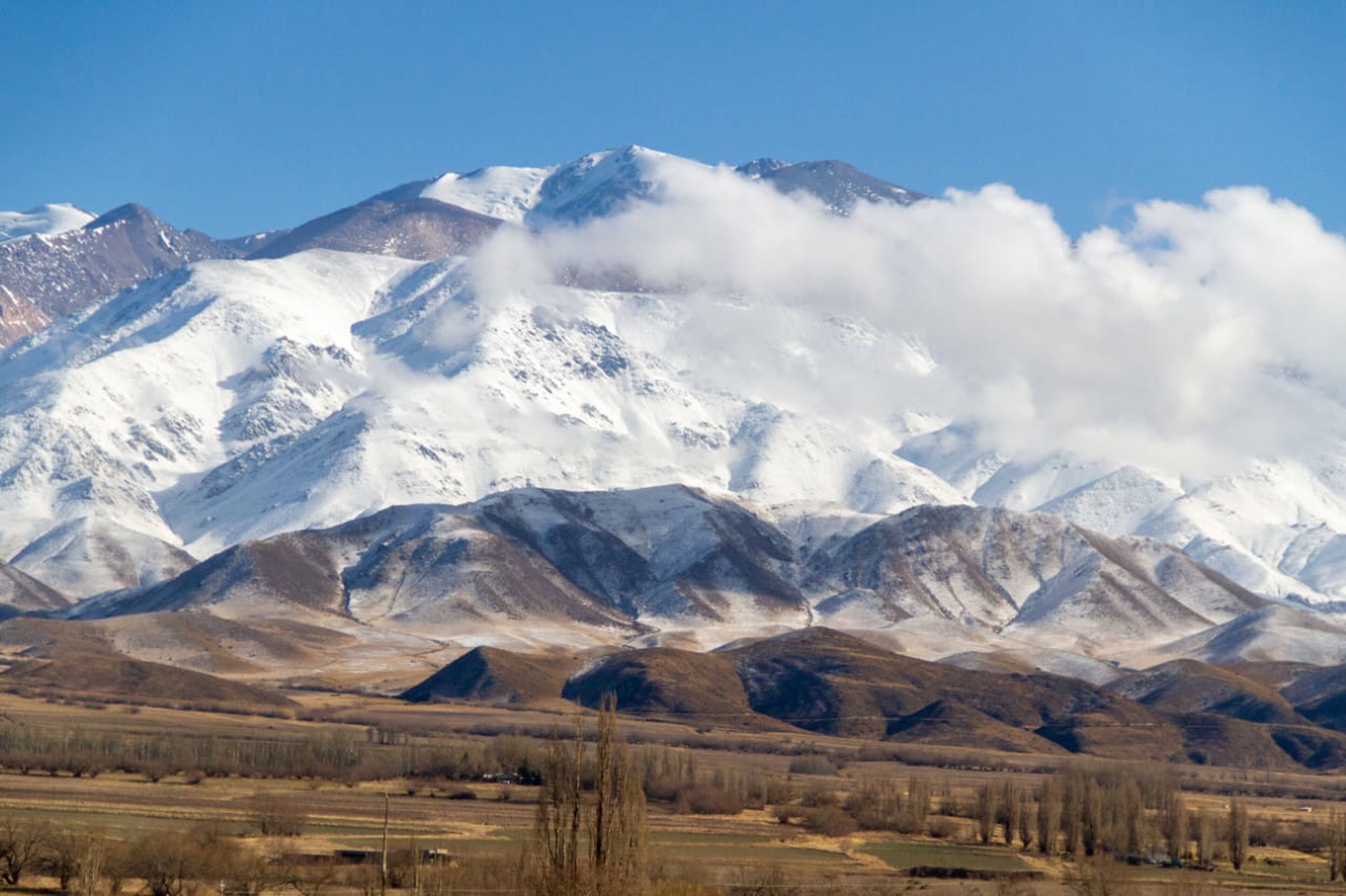 A mountainous landscape with snow-covered peaks and a valley below.