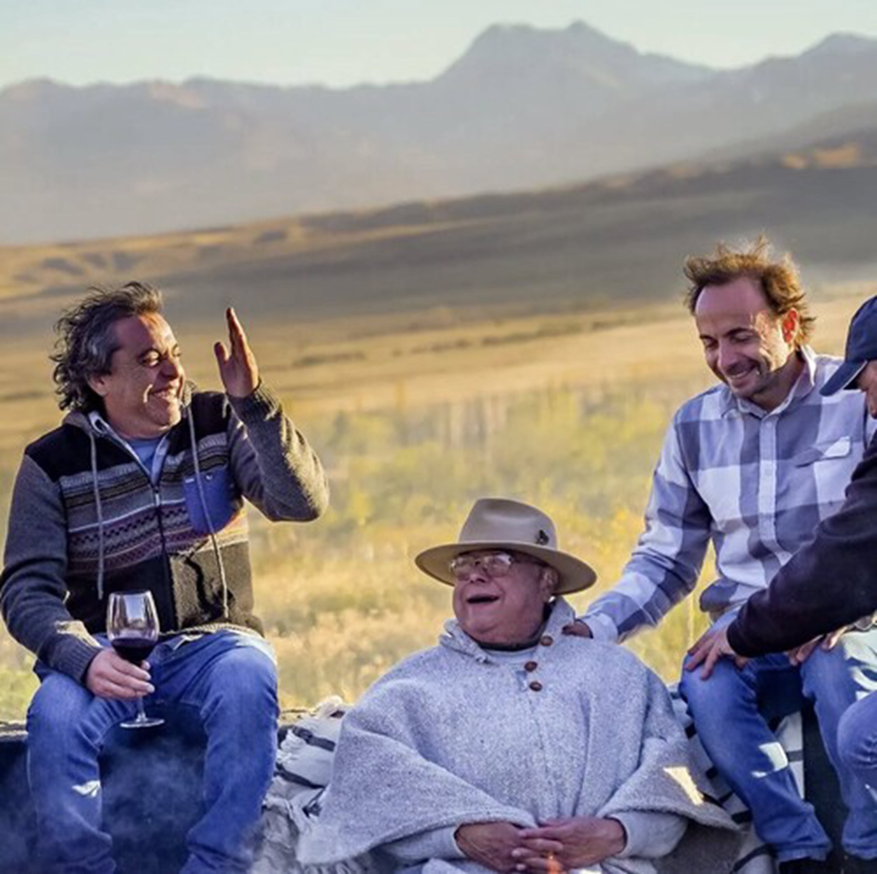 A group of people sitting outdoors with a mountainous backdrop.