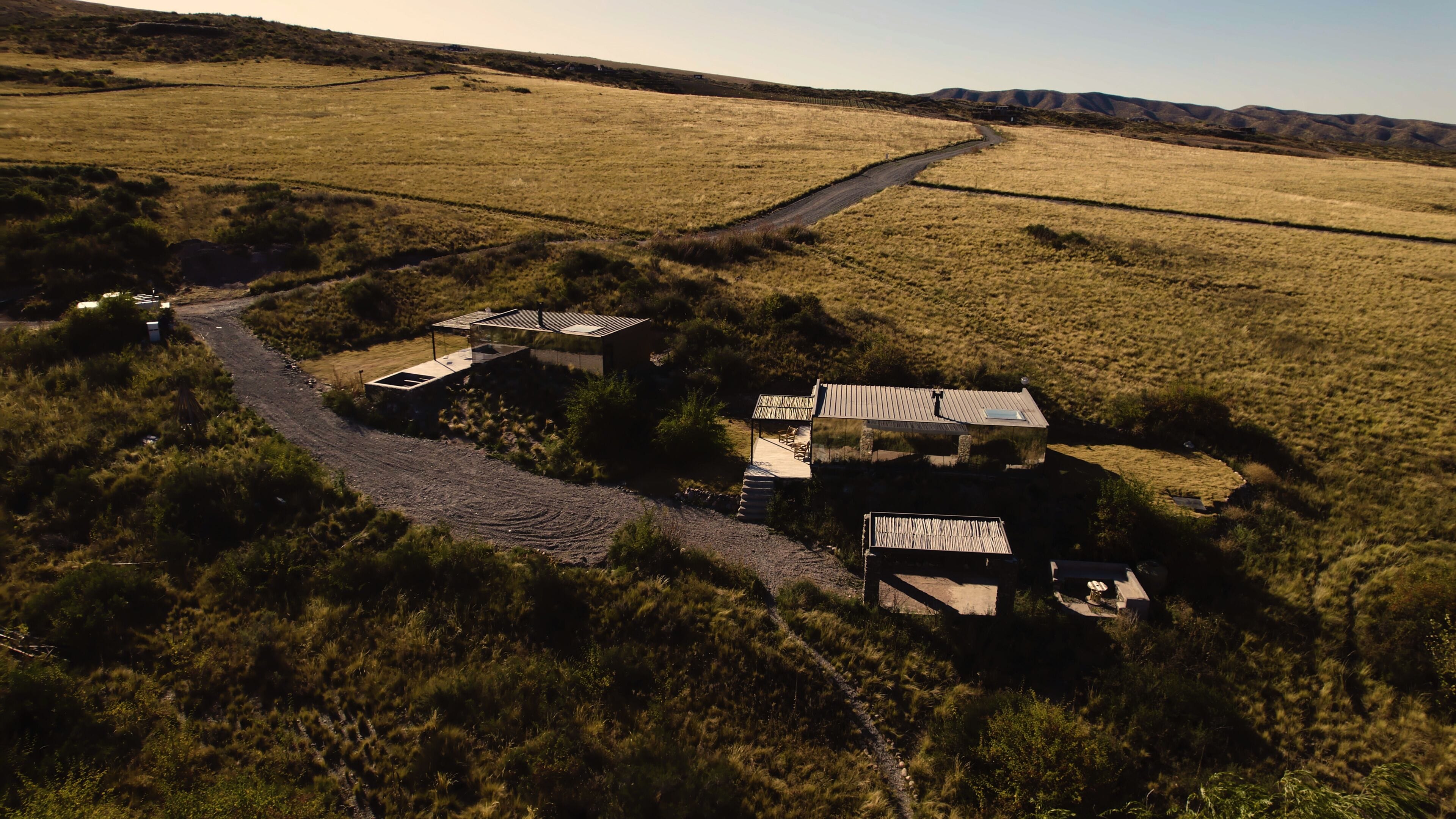 An aerial view of a rural property with a dirt road leading to a cluster of buildings.