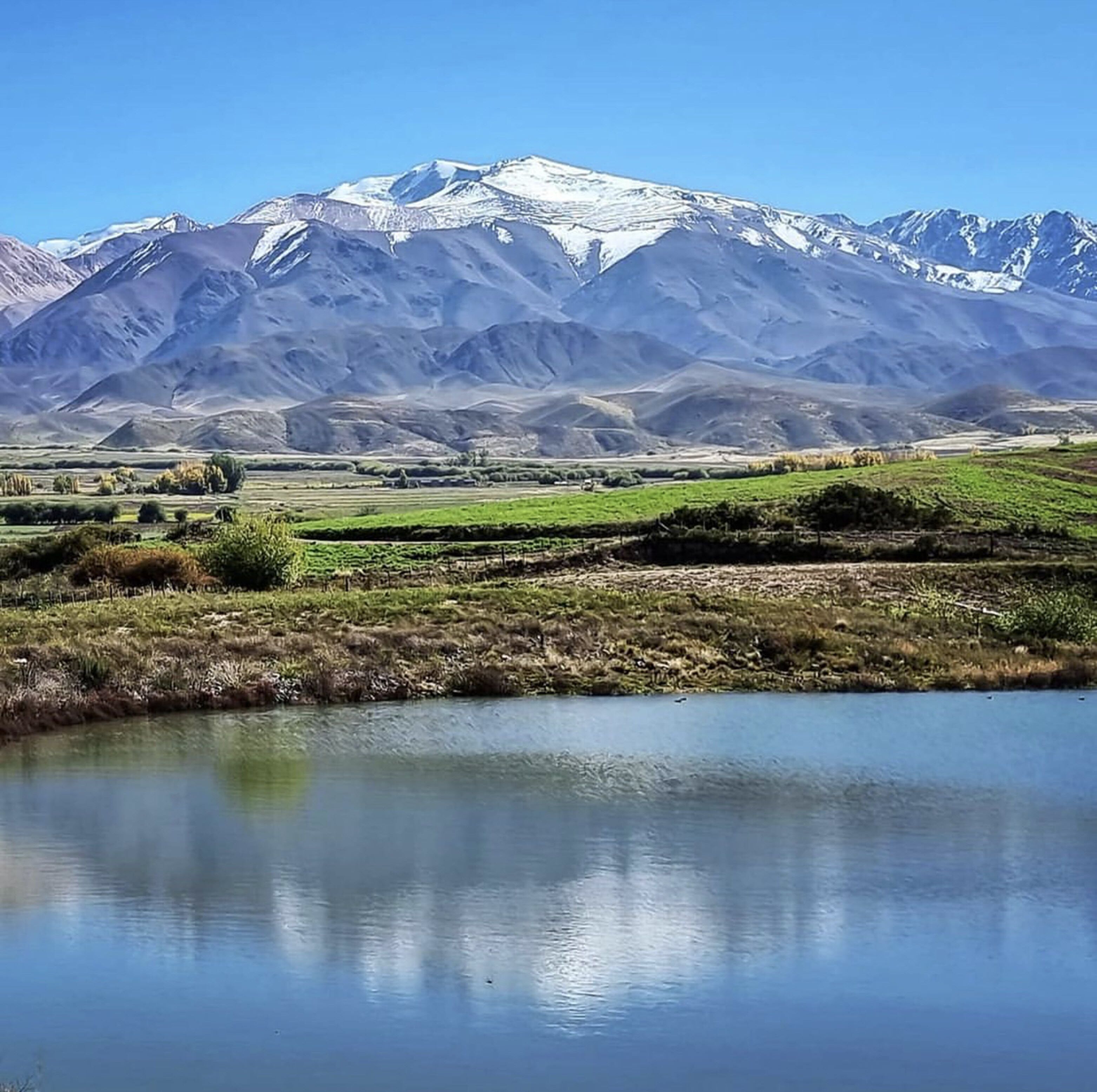 Un paisaje montañoso con una masa de agua al frente.