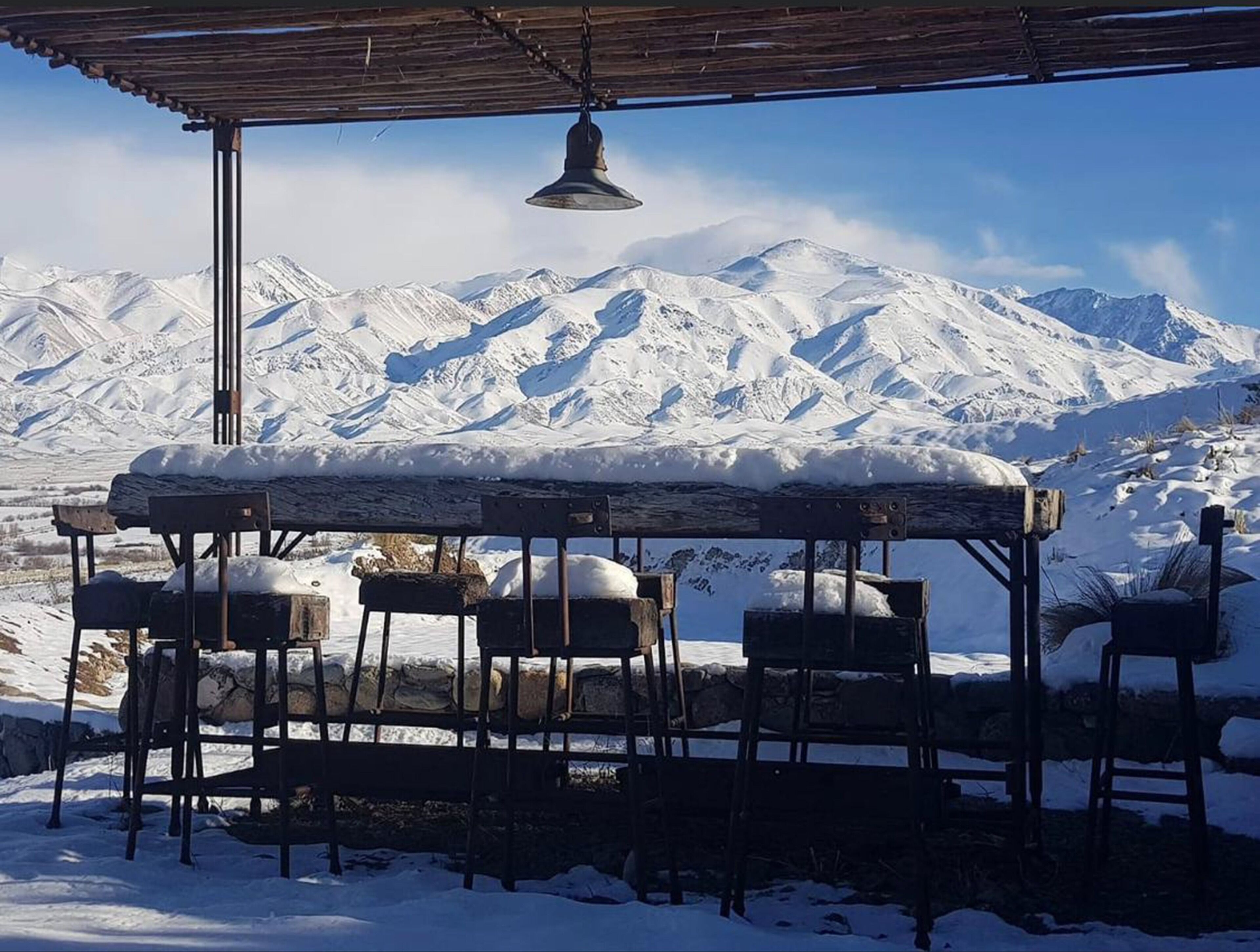 Een overdekt terras met uitzicht op besneeuwde bergen.