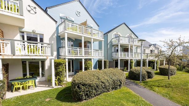 A two-story residential building with a balcony, a patio with outdoor furniture, and a well-maintained lawn. - Némo - Appartement avec Terrasse (Courseulles-sur-Mer)