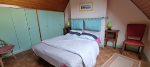 A bedroom with a bed, a wardrobe, a chair, a nightstand, and a lamp. - Two separate villas 100 meters from the beach in Trégunc (Trégunc)