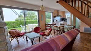 Un espai saló ampli amb una escala de fusta, una taula de dinar amb cadires i un sofà.