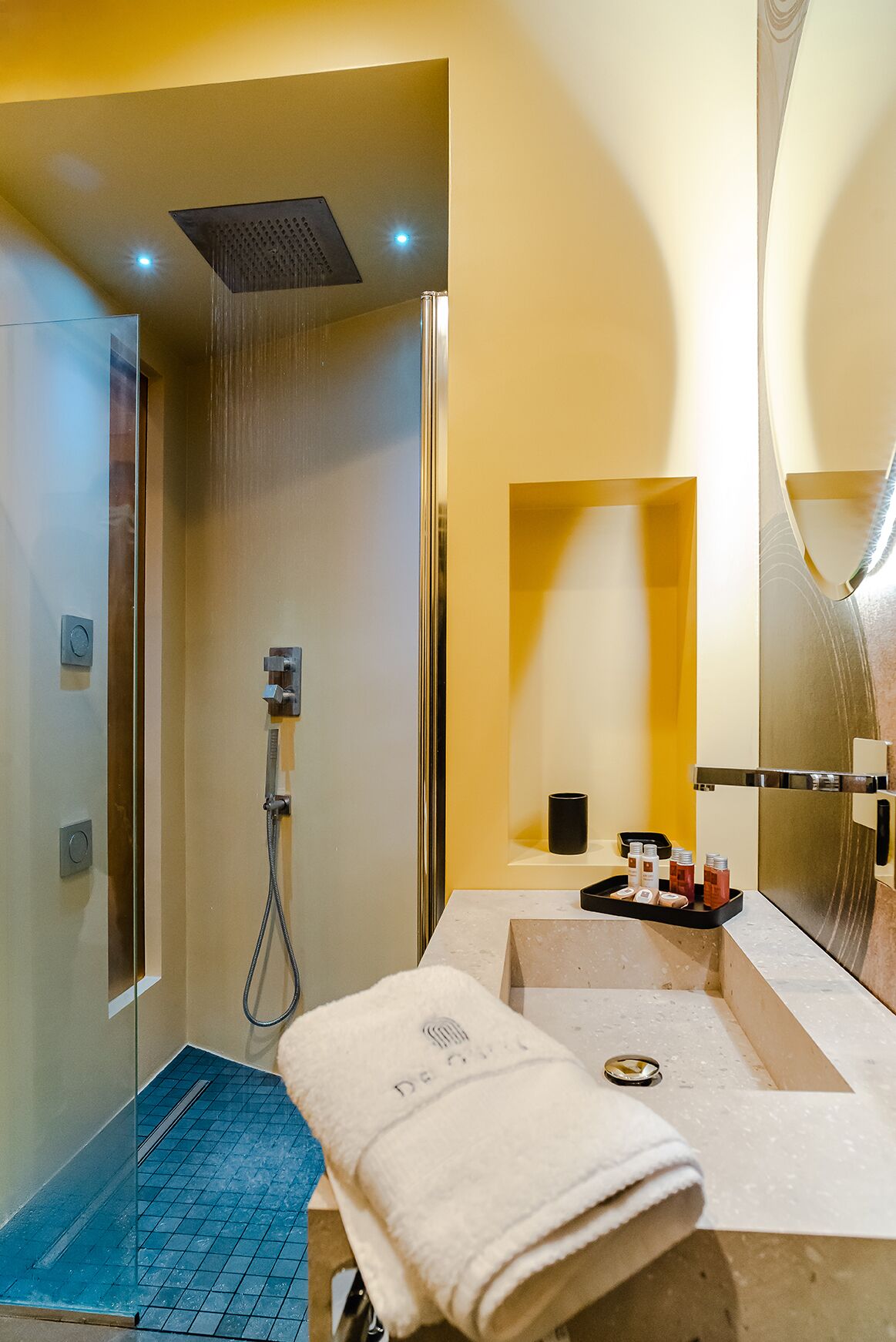 Une salle de bain moderne avec une douche à parois de verre, un lavabo avec un miroir et une serviette posée sur le comptoir.