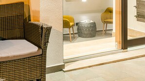 A modern interior with a glass door leading to a seating area with wicker furniture and a stone accent. - De Gulia Charme and Relax (Castellabate)
