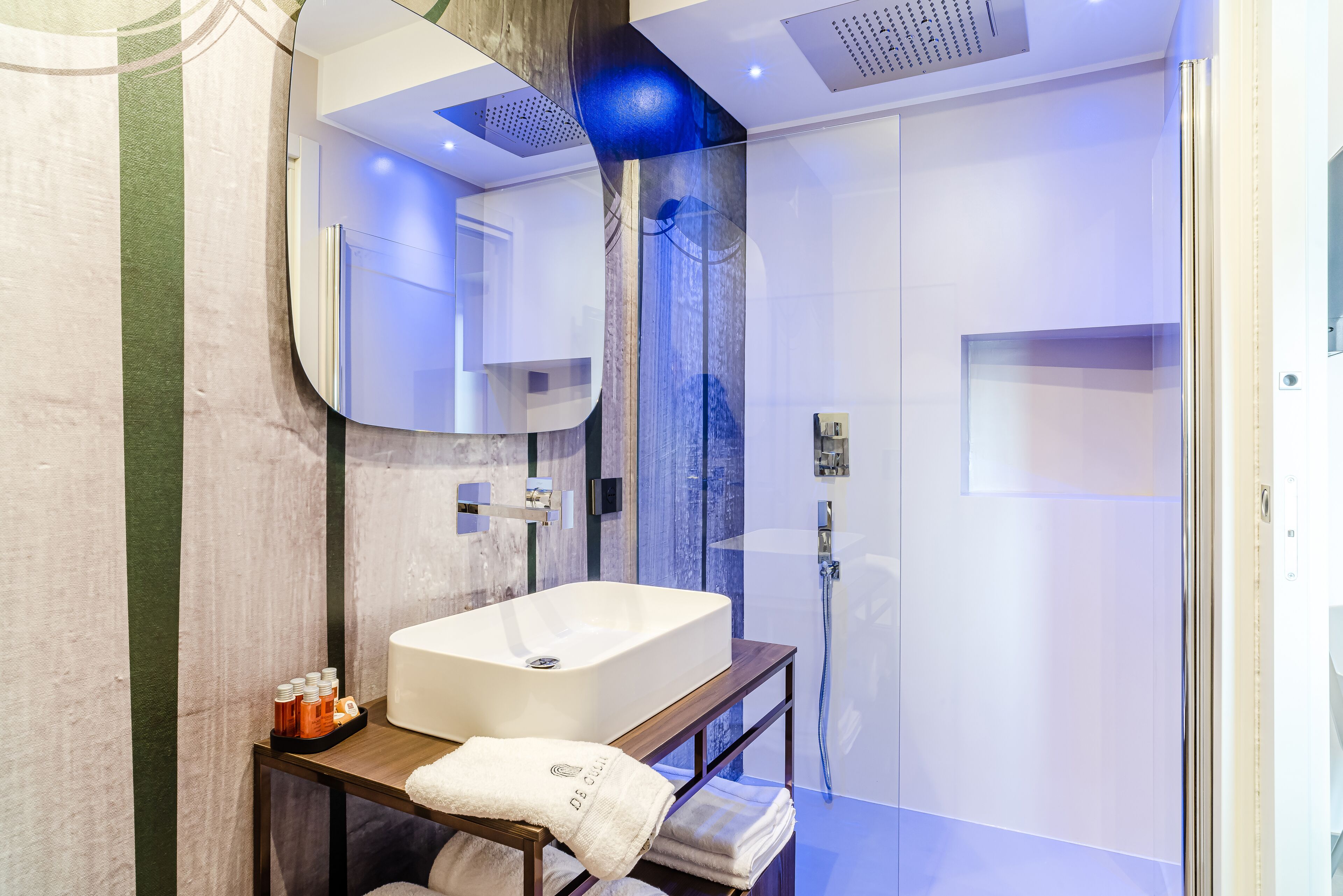 Un baño moderno con un espejo grande, un lavabo rectangular y una zona de ducha con mampara de vidrio.