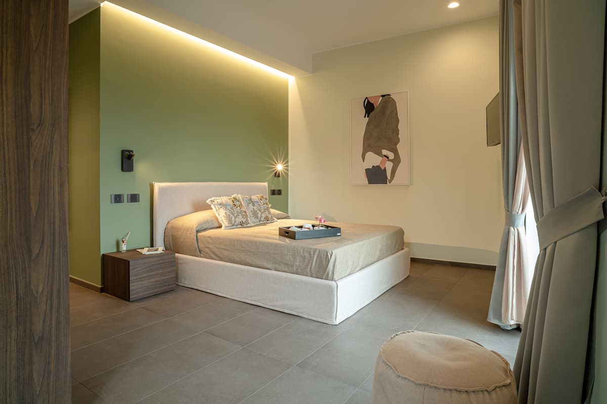 A modern bedroom with a large bed, bedside tables, and a wall-mounted artwork.