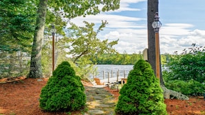 Un chemin de pierres menant à un quai au bord d’un lac, entouré d’arbres et d’un lampadaire.