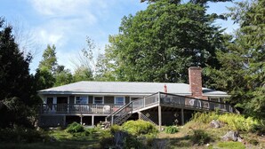 A two-story house with a covered porch and a brick chimney.