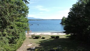 A lakeside view with picnic tables and a concrete path leading to the water.