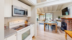 A modern kitchen with white cabinetry, stainless steel appliances, and a dining area with a wooden table and chairs.