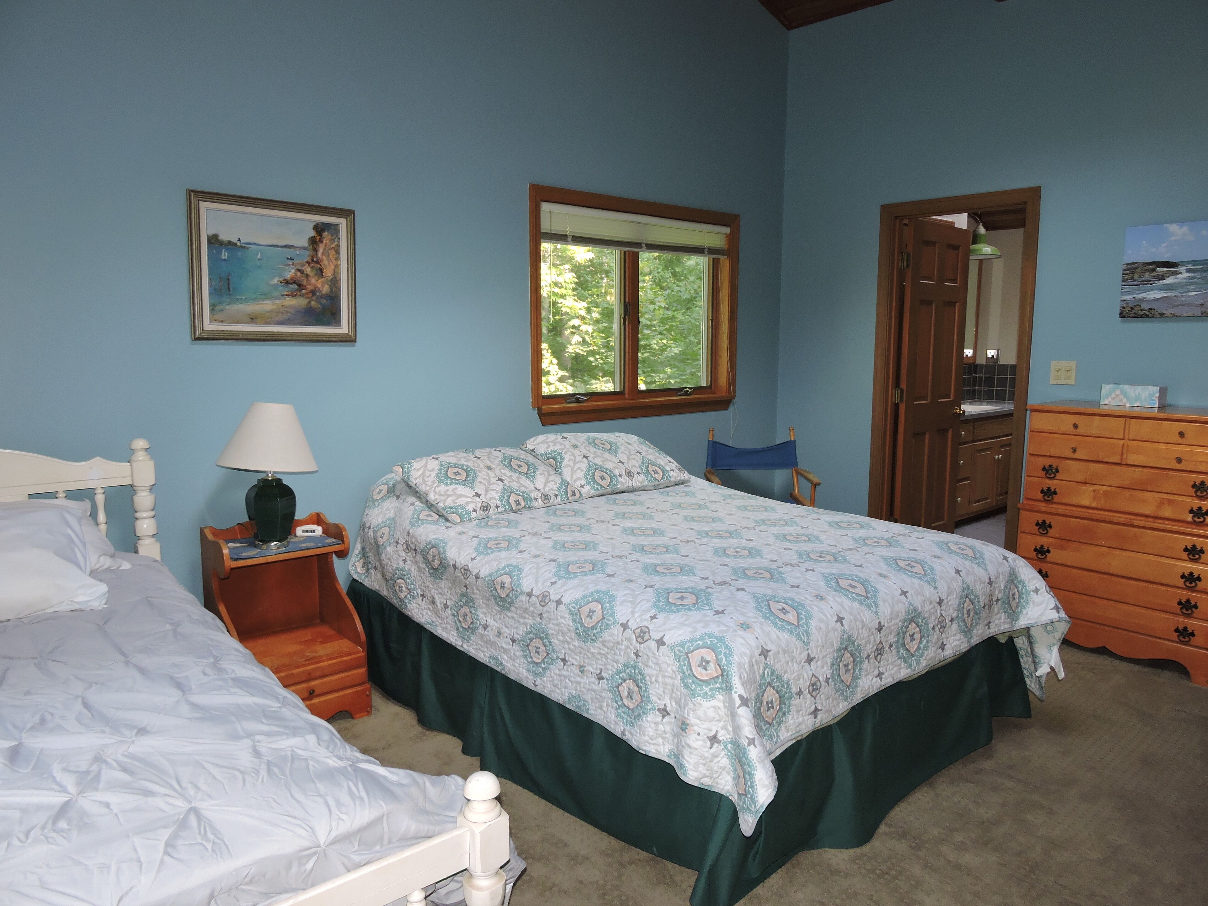 Un dormitorio con cama, mesita de noche, cómoda, silla y ventana.