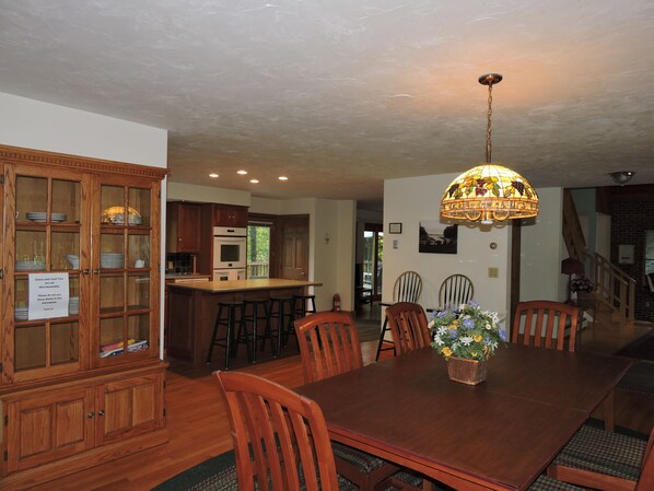A dining area with a wooden table, chairs, and a chandelier. - Large Suissevale Winnipesaukee Home 2 Minute Walk To Beach (Moultonborough)