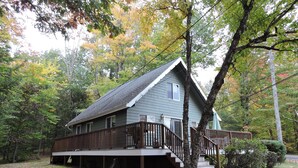 A two-story cabin with a wooden deck and stairs leading to a porch. - Directly Across Street From Suissevale Winnipesaukee Beach (Moultonborough)