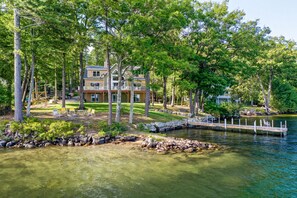 Une propriété au bord du lac, comprenant une maison à deux étages, un quai et une eau cristalline.