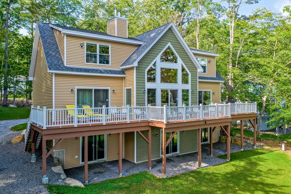 Une maison à deux étages dotée d’une terrasse, de grandes fenêtres et d’une cheminée.
