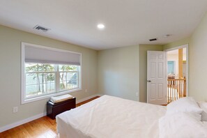 Une chambre avec une grande fenêtre, un lit et une porte donnant sur une autre pièce.