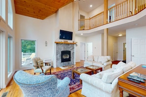 A spacious living room with a fireplace, a balcony, and a staircase leading to an upper level.