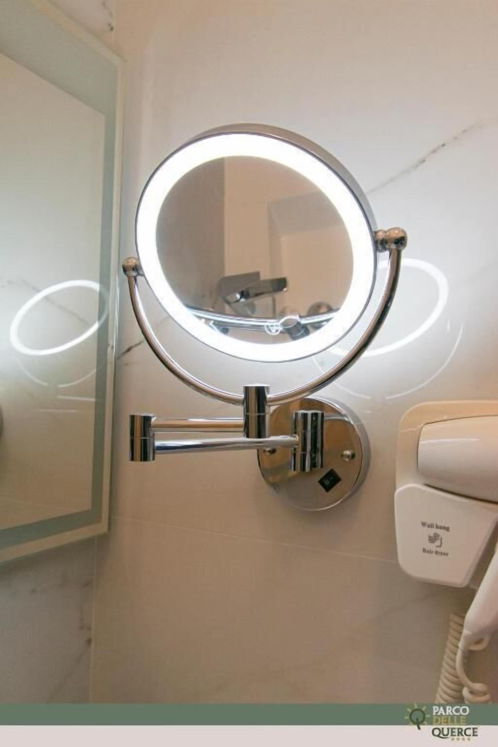 Un baño con un espejo montado en la pared, un secador de manos y un cambiador para bebés.