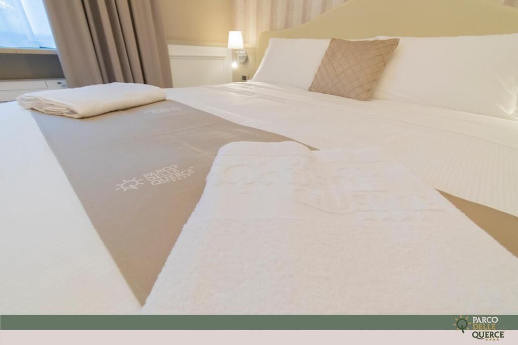 A neatly made bed with a folded towel and a decorative bed runner.