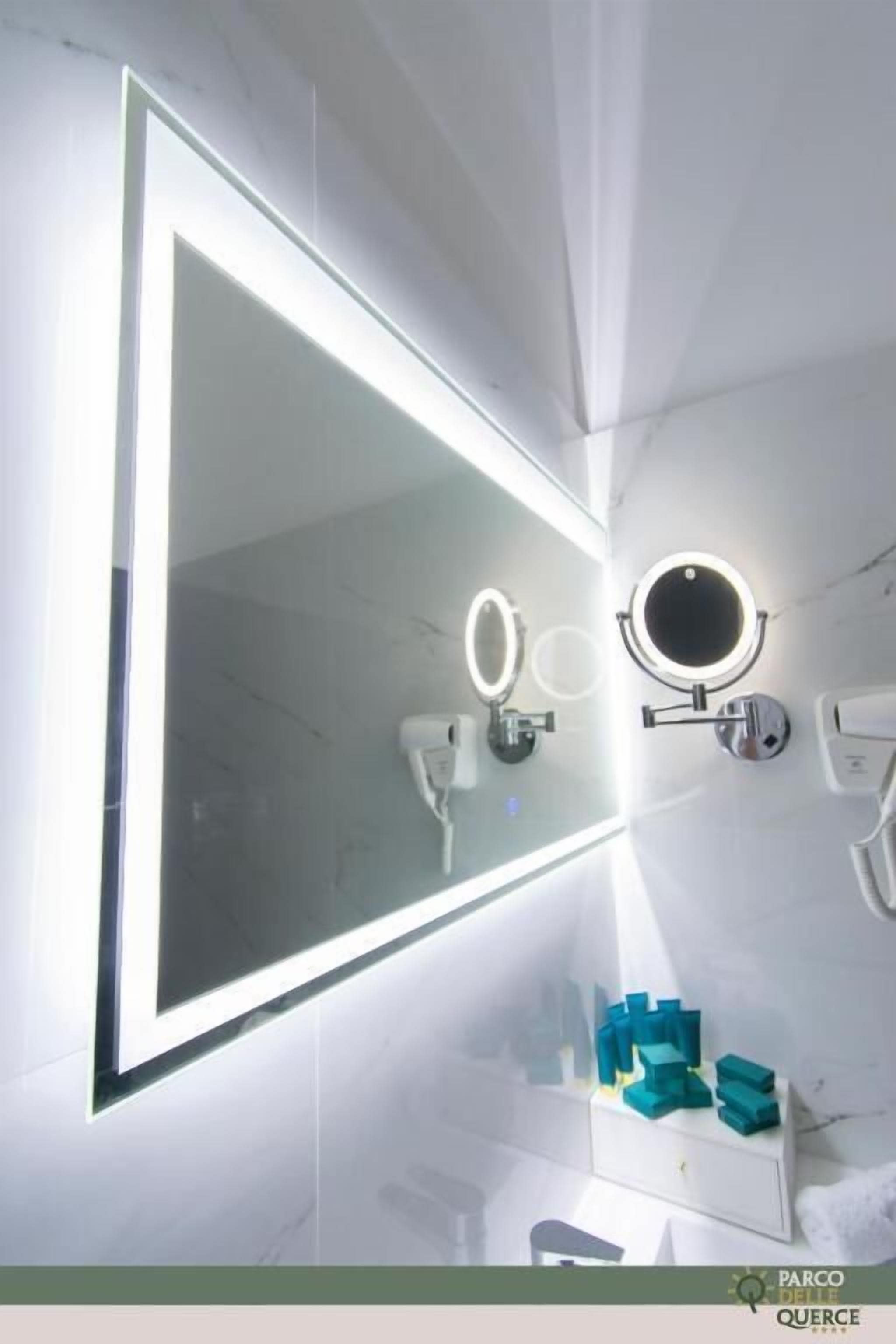 A bathroom with a large mirror, two wall-mounted lights, and a vanity with a mirror.