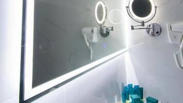A bathroom with a large mirror, two wall-mounted lights, and a vanity with a mirror.