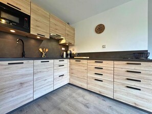 Una cocina moderna con armarios de madera, microondas y cafetera.
