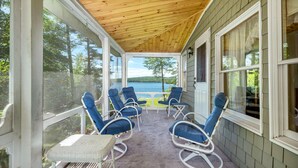 A covered porch with blue chairs and a table, overlooking a lake. - Winnipesaukee Home PLUS Apartment For 10 Beach Dock Sunsets AUG 29TH SPECIAL (Moultonborough)