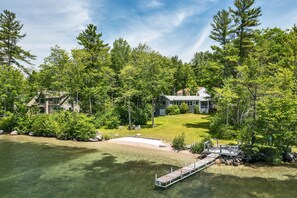A lakeside property with a dock, a grassy yard, and two houses surrounded by dense trees. - Winnipesaukee Home PLUS Apartment For 10 Beach Dock Sunsets AUG 29TH SPECIAL (Moultonborough)