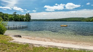 A lake with a wooden dock extending into the water, surrounded by greenery and a clear sky. - Winnipesaukee Home PLUS Apartment For 10 Beach Dock Sunsets AUG 29TH SPECIAL (Moultonborough)