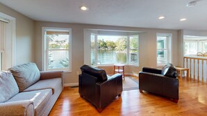 A spacious living area with a large window overlooking a body of water, a sofa, and a coffee table. - Winnipesaukee Waterfront in Meredith for 10 (Meredith)