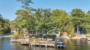 A lakeside dock with boats, a wooden deck, and a building with a deck and outdoor seating.