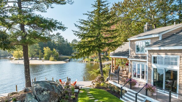 A lakeside property with a deck, a stone pathway, and a view of the water.