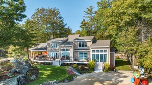 A modern two-story house with a covered patio, a pond, and a well-maintained garden.