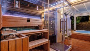 Un área de spa moderna con un jacuzzi, bancos de madera y una ducha con paredes de vidrio.