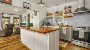 A modern kitchen with a central island, stainless steel appliances, and decorative items on shelves. - READY TO RELAX?  Lake front house w/ beautiful Sunsets on Lake Greenwood (cross Hill)