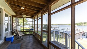 A covered deck with a view of a lake, wooden railings, and outdoor furniture. - READY TO RELAX?  Lake front house w/ beautiful Sunsets on Lake Greenwood (cross Hill)