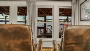 A room with two leather chairs facing a large window with a view of a dock and boats. - READY TO RELAX?  Lake front house w/ beautiful Sunsets on Lake Greenwood (cross Hill)