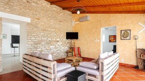 Un intérieur rustique avec un mur en pierre, un plafond en bois et un téléviseur fixé au mur.