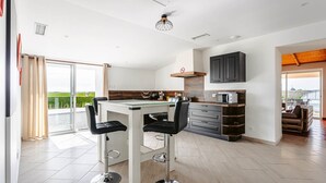 Une cuisine moderne dotée d’un îlot central, de tabourets de bar et offrant une vue sur la verdure environnante.