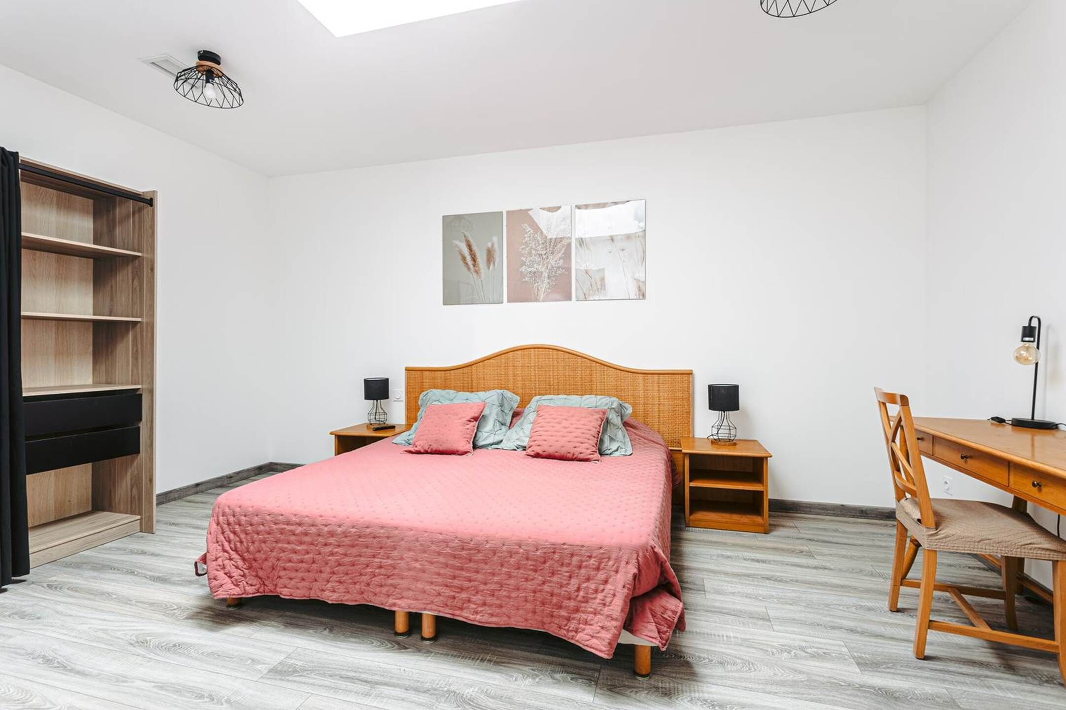 A bedroom with a bed, bedside tables, a desk, and a chair.