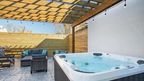 Ett bubbelbad under en träpergola med utemöbler.