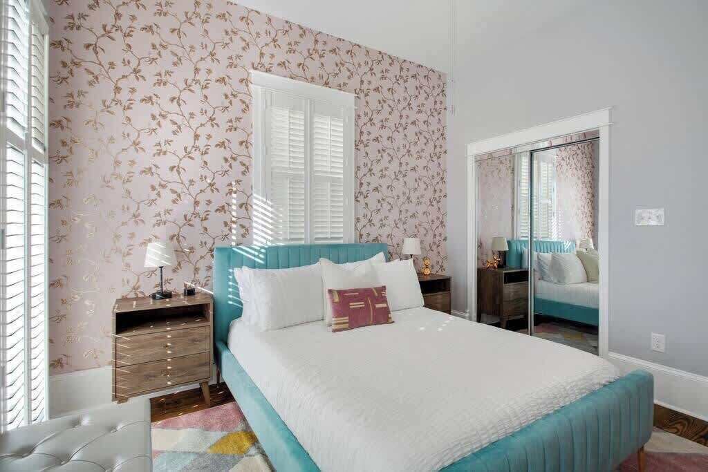 Un dormitorio con cama, mesitas de noche, cómoda y espejo.