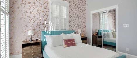 Un dormitorio con cama, mesitas de noche, cómoda y espejo.
