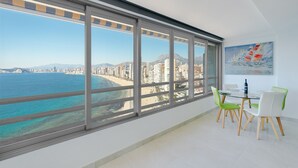 Una habitación moderna con un ventanal que da a una playa y al paisaje urbano.