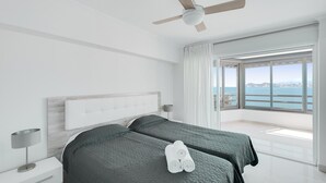 Un dormitorio moderno con una cama grande, un ventilador de techo y vista al mar.