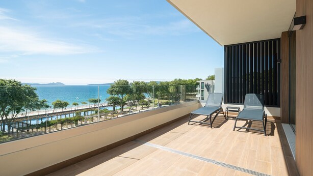 Un balcón con vistas al mar, una piscina y un edificio moderno.
