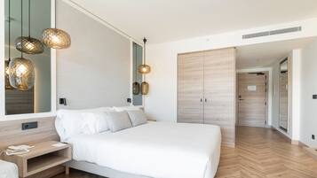 Une chambre moderne avec un grand lit, des tables de chevet, une armoire et des luminaires suspendus.