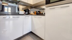 A modern kitchen with white cabinets, a built-in oven, and a stainless steel range hood. - N&J - LE SALEYA - Old Town - Very close sea (Niza)
